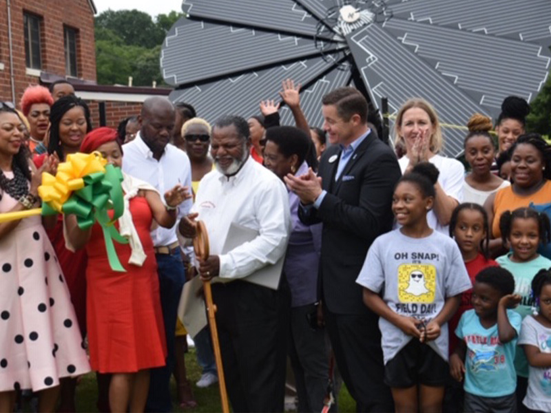 Group of people celebrating in front of a solar panel.